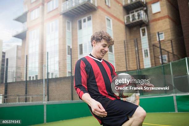 Young man practising football skills on urban football pitch
