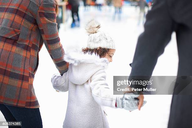 rear view of girl ice skating with parents, holding hands - ice rink uk stock pictures, royalty-free photos & images