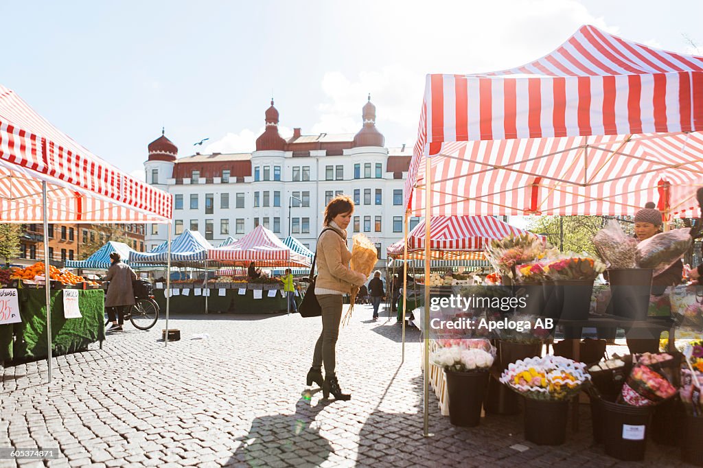 Full length side view of woman buying flowers at market stall