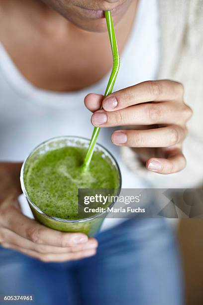 woman drinking green smoothie with straw - detox drink stock pictures, royalty-free photos & images