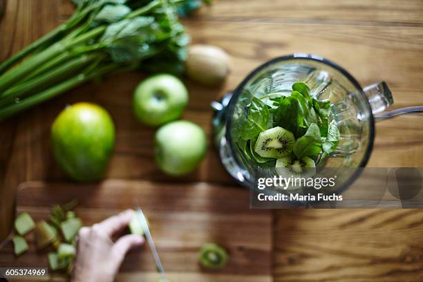 woman cutting green kiwi on wooden table - detox stock-fotos und bilder