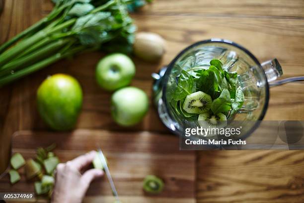 woman cutting green kiwi on wooden table - detox bildbanksfoton och bilder