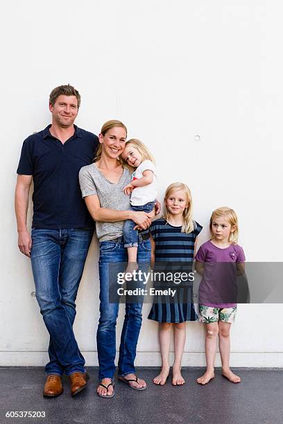 portrait of parents and three young daughters standing in front of white wall - family with three children fotografías e imágenes de stock
