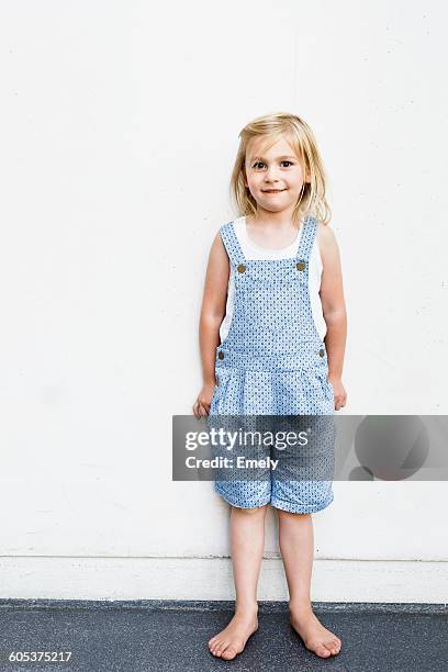 portrait of girl wearing dungarees in front of white wall - dungarees stock-fotos und bilder