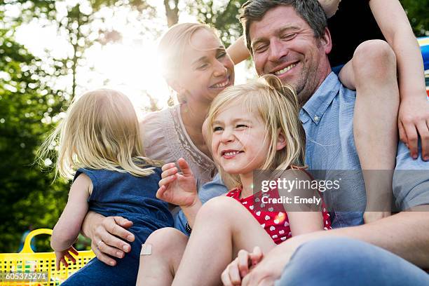 happy parents and three daughters sharing family picnic in park - family picnic stock-fotos und bilder