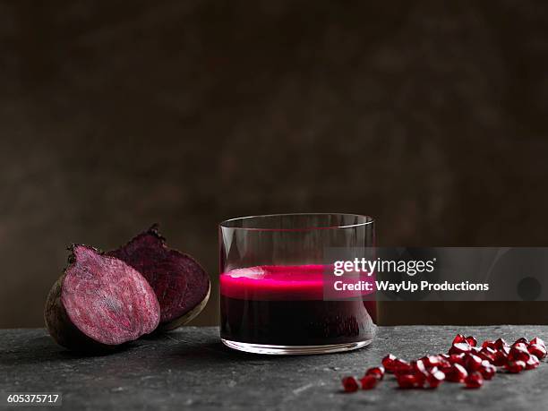 purple raw beetroot and apple juice, halved beetroot and pomegranate seeds - beetroot juice stock-fotos und bilder