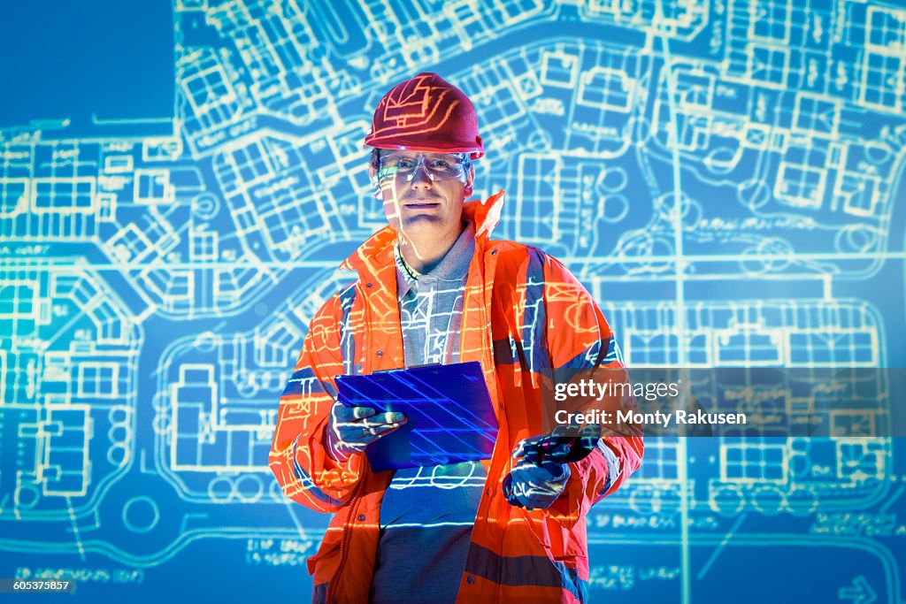 Engineer with digital tablet and projected plans, portrait