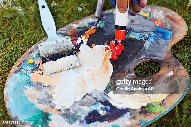 cropped hand spilling red paint from tube on messy palette - female anatomy for artist stock pictures, royalty-free photos & images