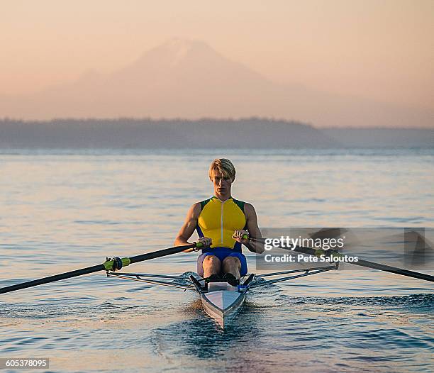 teenage boy in sculling boat on water - single scull stockfoto's en -beelden