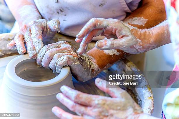 close up of female potter and mature student hands making pot on potters wheel - potters wheel stock pictures, royalty-free photos & images