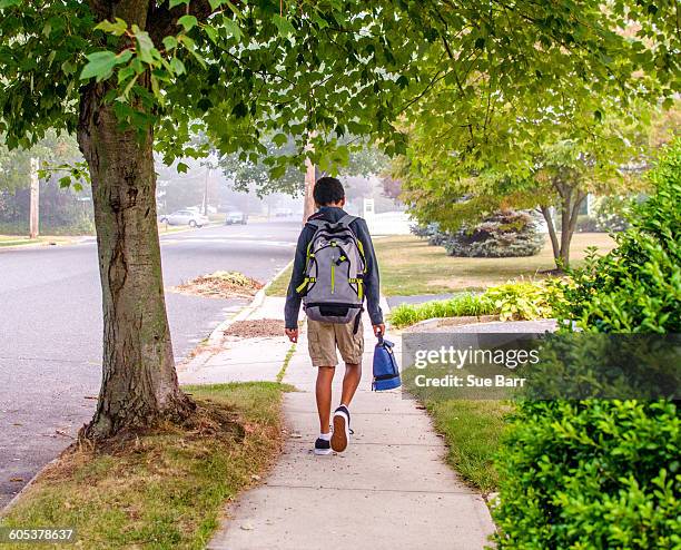 boy with backpack walking on sidewalk - walking boy school stock pictures, royalty-free photos & images