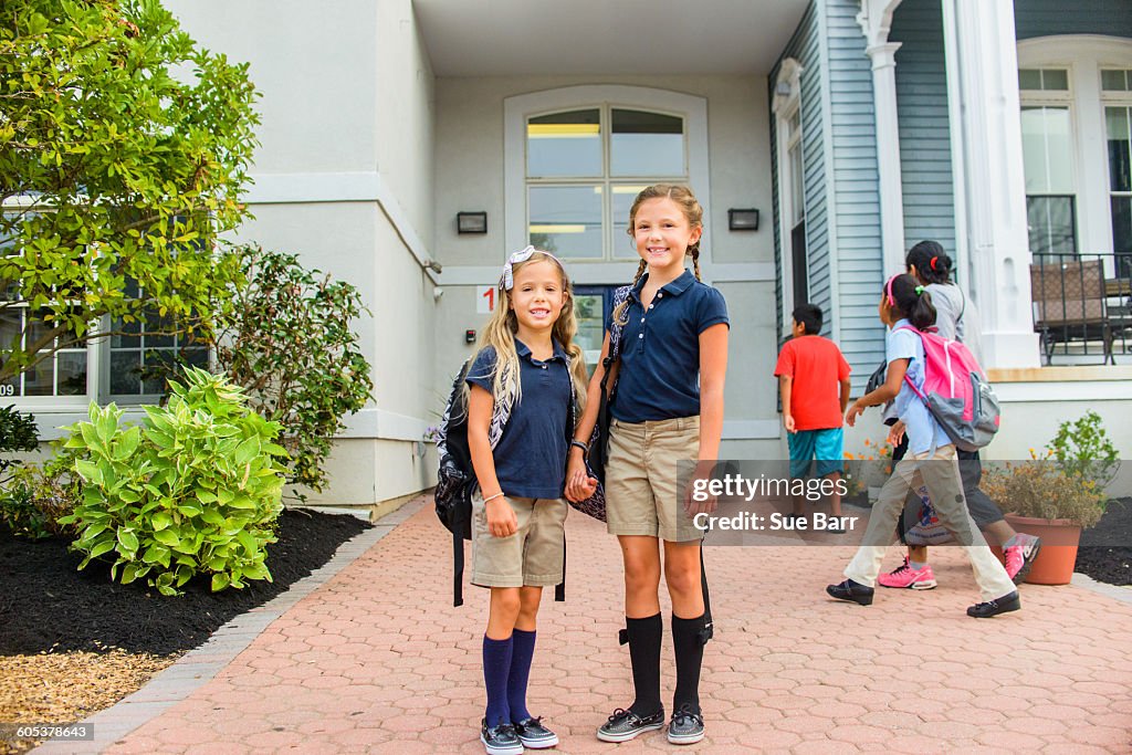 Happy girls standing in front of school