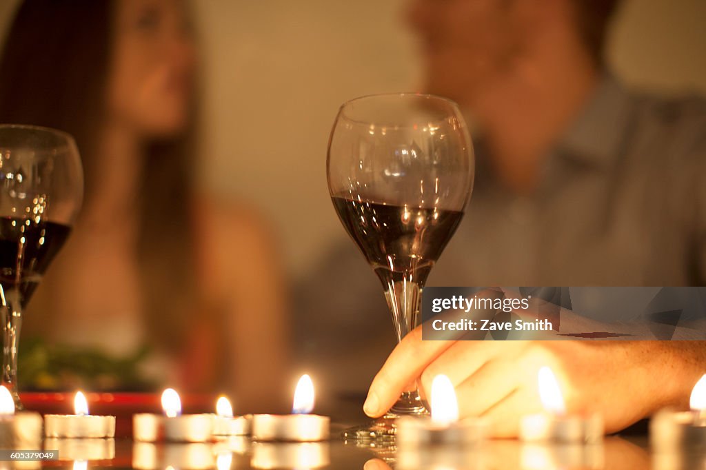 Couple enjoying a glass of red wine by candlelight