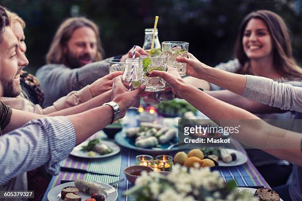 happy friends toasting mojito glasses at dinner table in yard - cocktail party at home stock pictures, royalty-free photos & images