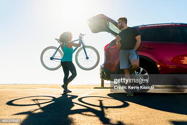 mid adult woman putting bicycle into car boot - daily life in southern california stockfoto's en -beelden