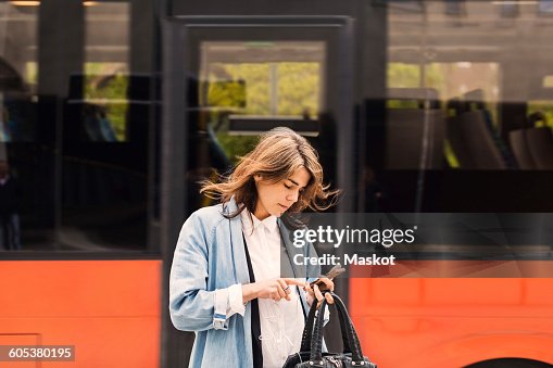 Young woman using mobile phone against bus Young woman using mobile phone against bus