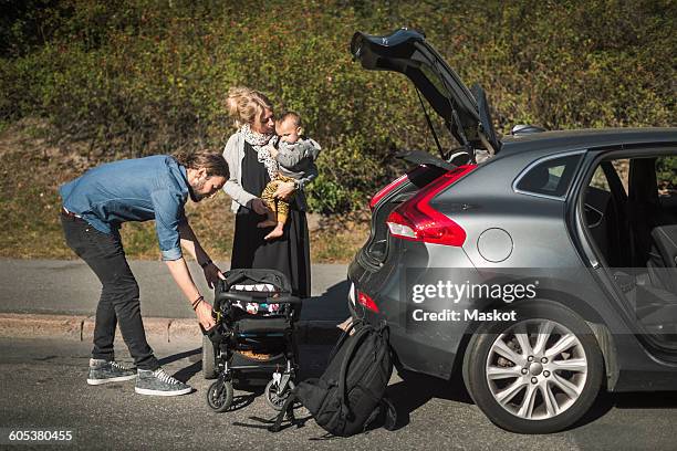 mid adult parents with son and baby carriage near car on street - baby boot stock pictures, royalty-free photos & images