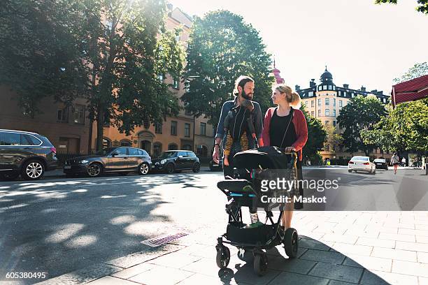 mid adult parents with baby boy and stroller walking on sidewalk in city - stroller stock pictures, royalty-free photos & images
