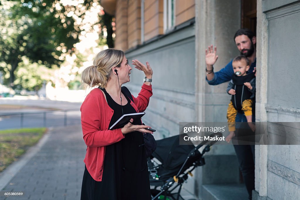 Mid adult mother waving family while leaving for work