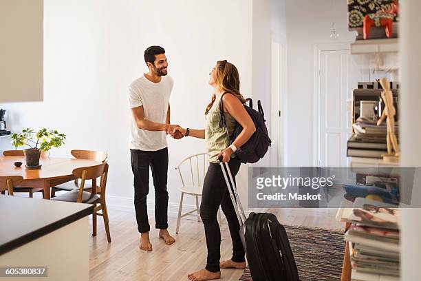 happy man shaking hand with woman going for vacation - economía colaborativa fotografías e imágenes de stock