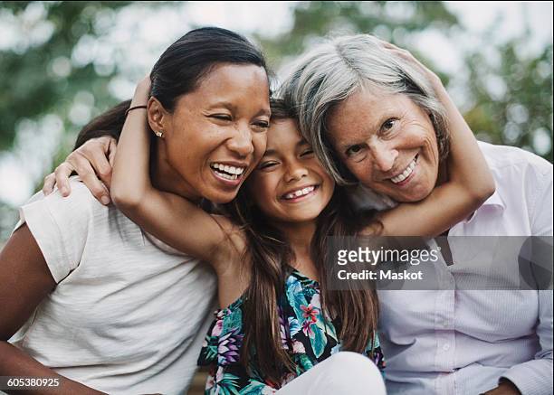 Portrait of happy girl embracing mother and grandmother at yard