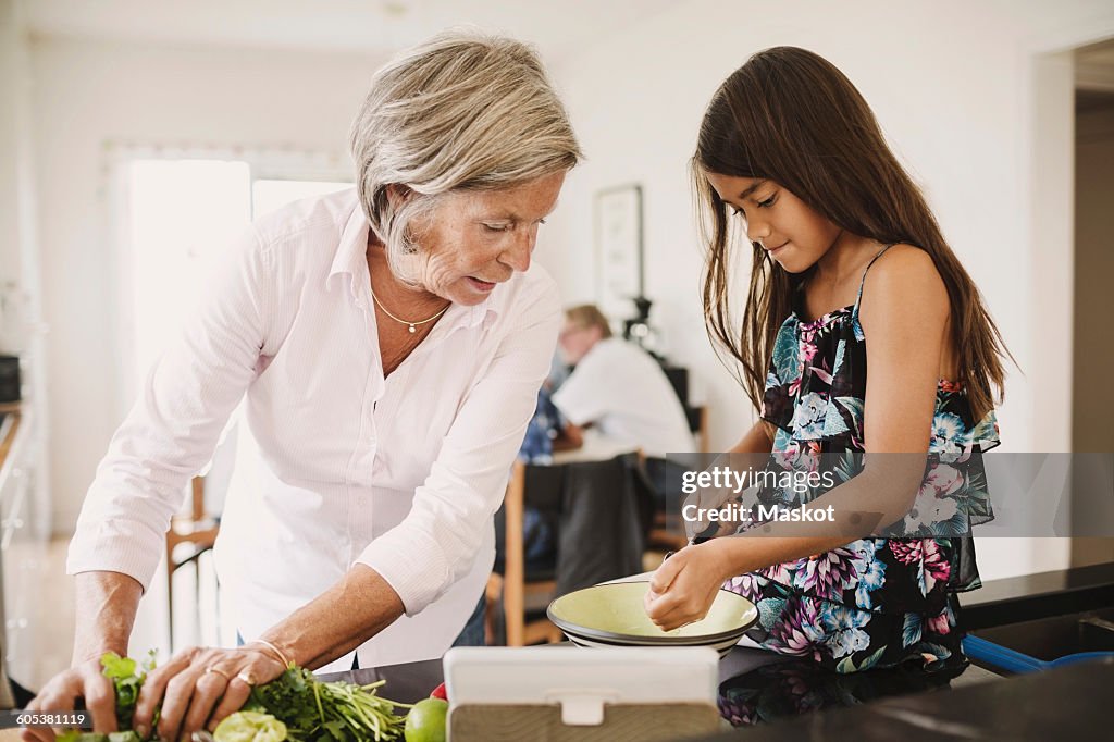 Granddaughter and grandmother preparing food in kitchen