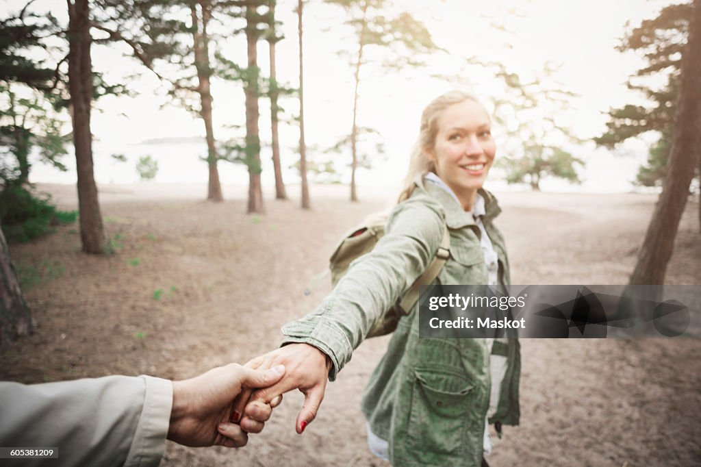 Happy woman holding mans hand in forest
