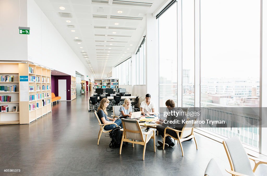 Young college friends studying together in library