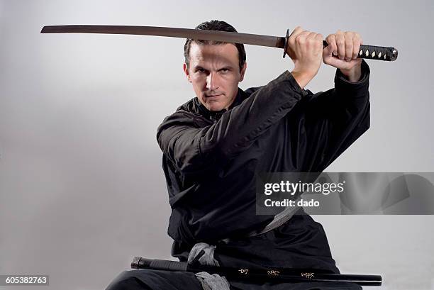 man dressed as a samurai holding katana in the air - samurai stock pictures, royalty-free photos & images