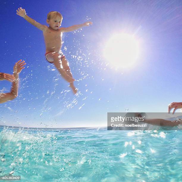 father and son throwing baby brother in the air in the sea - dad throwing kid in air stockfoto's en -beelden