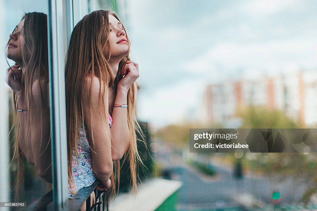 Young woman leaning out of a window in city, Seville, Spain