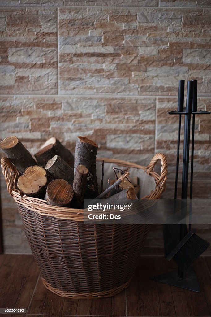 Firewood in a basket next to a hearth set