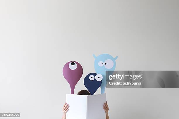 woman reading book with friendly monsters popping up - fantasy stock-fotos und bilder