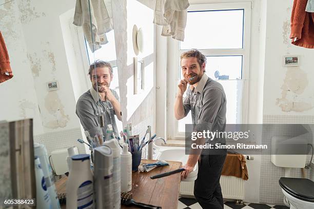 handsome young man brushing teeth in bathroom - halle an der saale 個照片及圖片檔