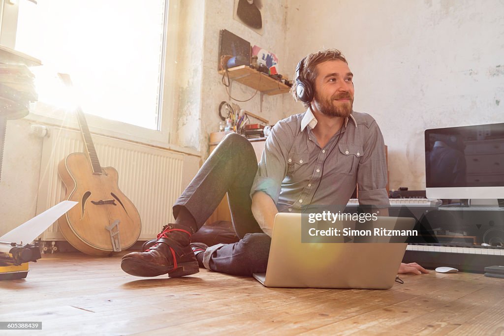 Handsome musician with headphones using laptop