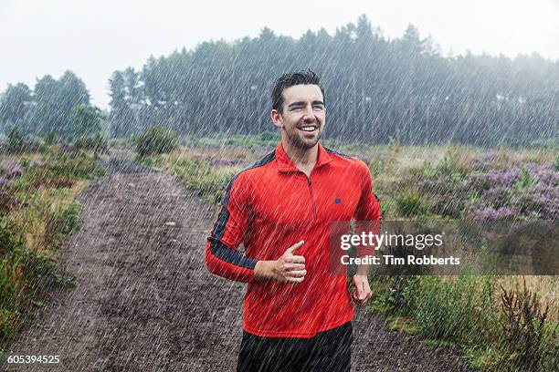 jogger running on path in rain. - hombre mojado fotografías e imágenes de stock