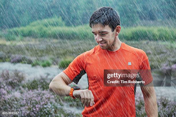 athlete with smart watch in rain - tijdmeter stockfoto's en -beelden