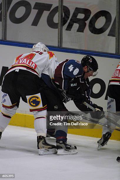 Forward Alex Tanguay of the Colorado Avalanche battles for puck possession as defenseman Par Djoos of Brynas tries to push him off the puck during...