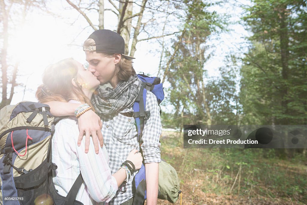 Young couple hiking with backpack and kissing in a forest, Bavaria, Germany