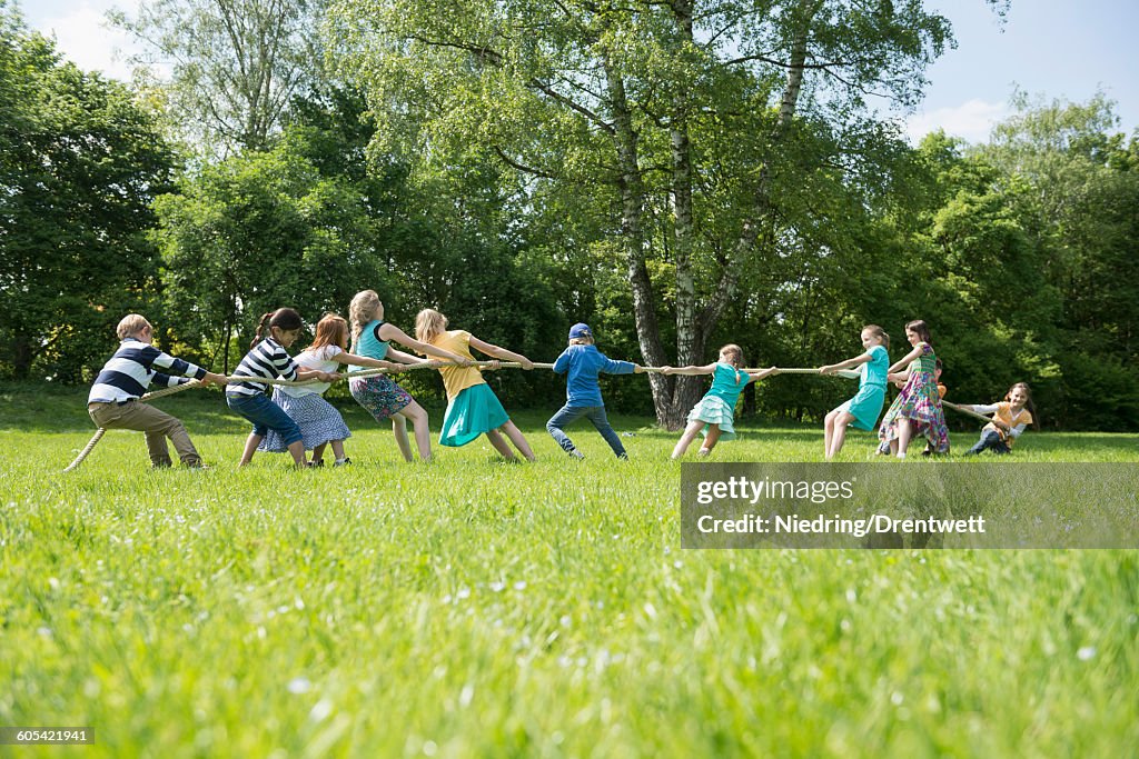 Group of children playing tug-of-war in a park, Munich, Bavaria, Germany