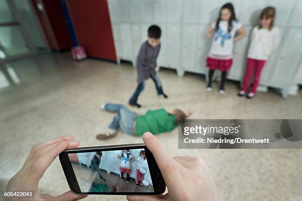 persons hand filming two schoolboys fighting in school corridor with mobile phone, bavaria, germany - fighting group stockfoto's en -beelden