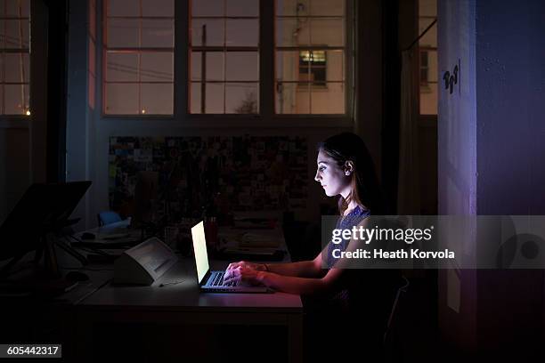 young employee working late on computer in dark. - laptop dark stock pictures, royalty-free photos & images