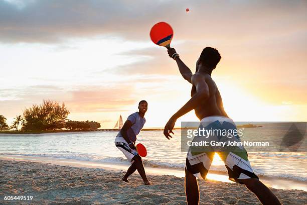 Two young men playing beach tennis at sun