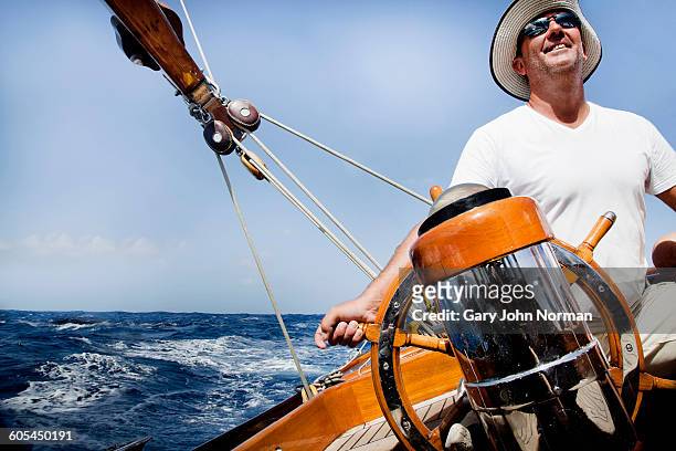 happy skipper at helm of classic yacht - チームキャプテン ストックフォトと画像