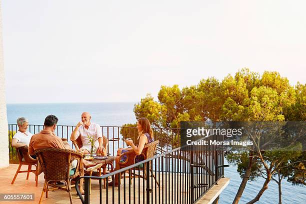 friends sitting on terrace surrounded by ocean - four day old stock pictures, royalty-free photos & images