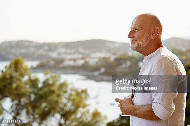 thoughtful senior man holding wineglass - sunny side stock pictures, royalty-free photos & images