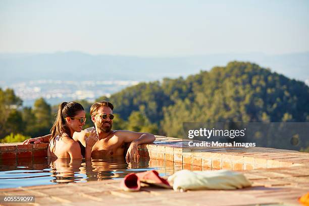 couple looking away while enjoying in pool - poolside stock pictures, royalty-free photos & images