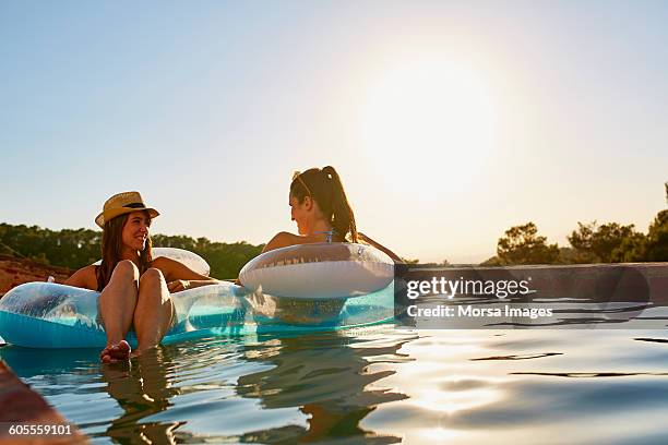 friends in inflatable ring floating on pool - airbed stock pictures, royalty-free photos & images