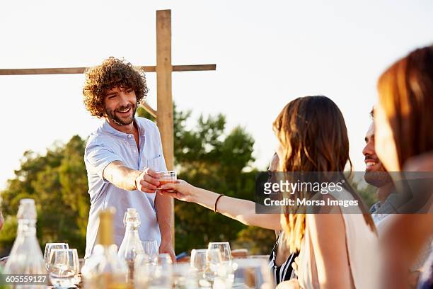 man passing drink to friend at social gathering - vinger bildbanksfoton och bilder