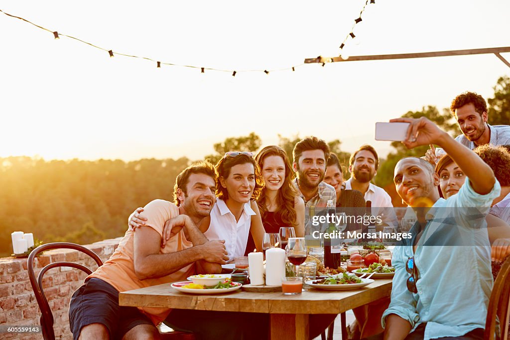 Man taking group selfie on mobile phone at party